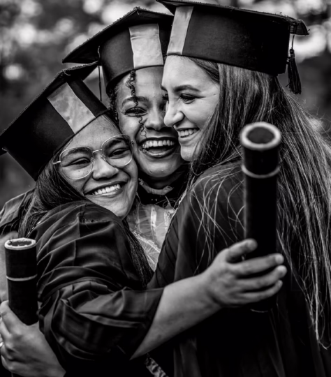 Three college graduates embracing.
