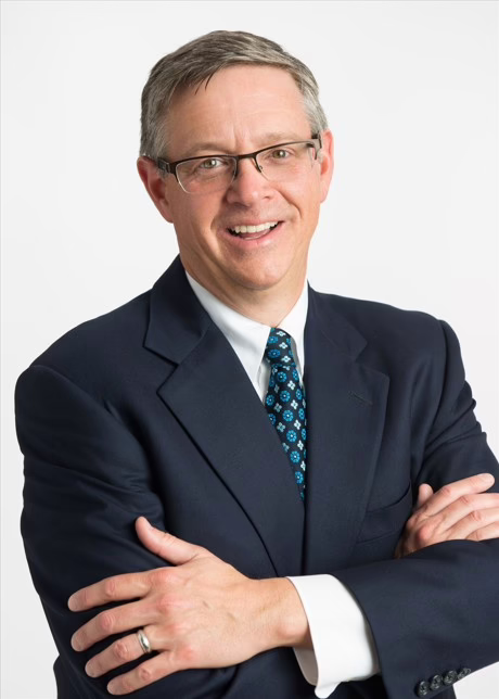 John Pelletier standing with arms crossed over his shoulders smiling