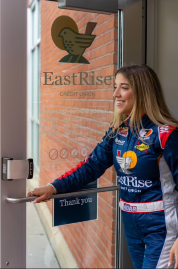 Taylor Hoar walking out of an EastRise branch, holding the door in her right hand open as she walks through