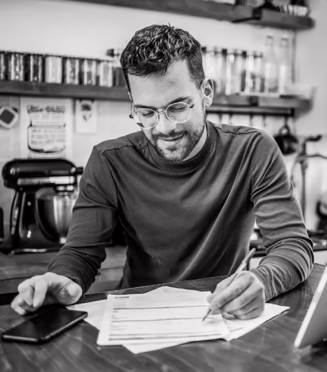 A man sits at a desk reviewing financial documents.