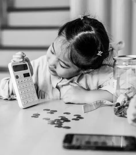 Young child playing with a calculator and coins.