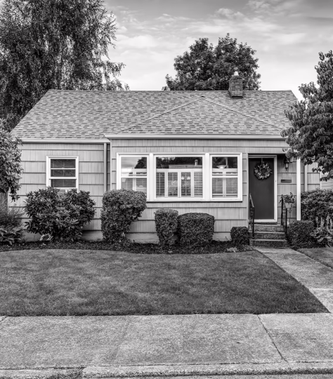 cape-style house with bushes and grass outside