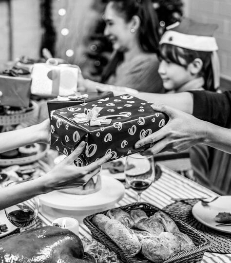 Hands passing a gift across a table during the holidays