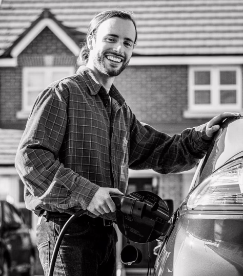 Man charging electric vehicle and smiling