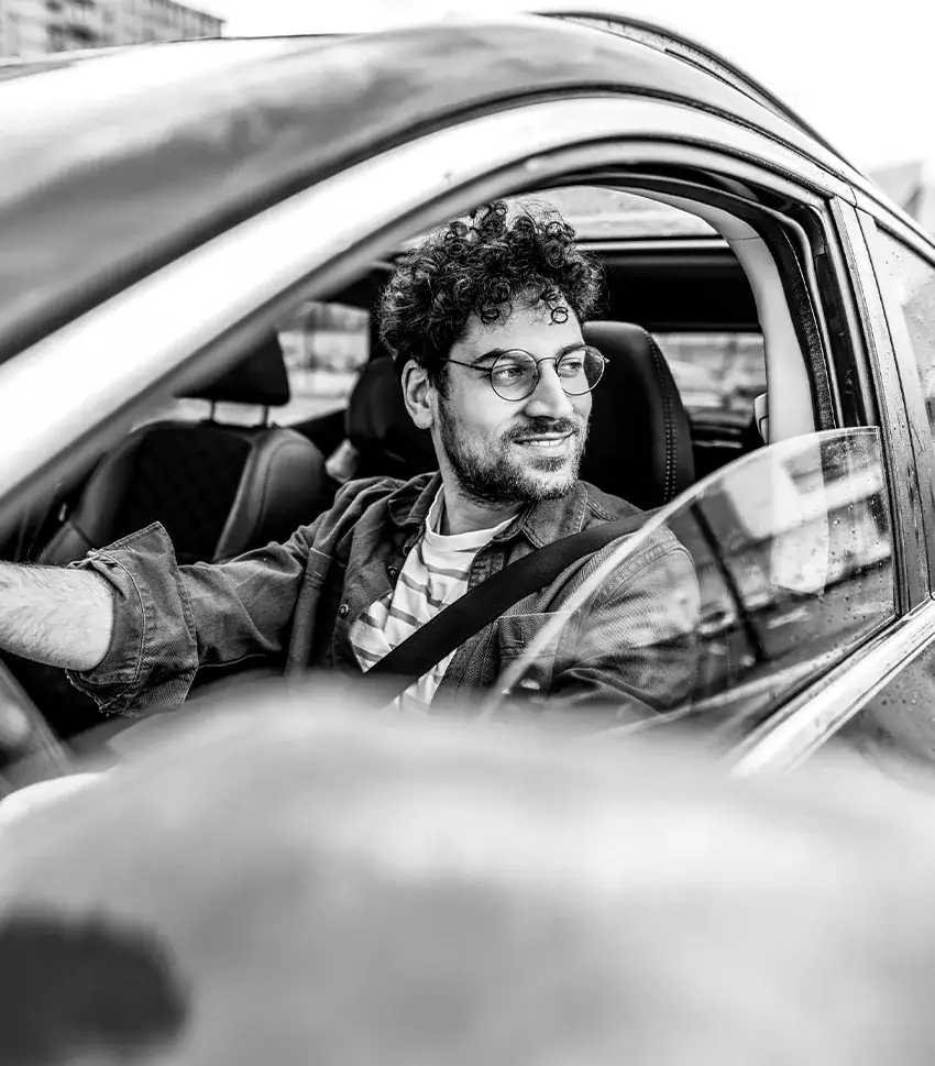 Man driving a car looking out the window and smiling