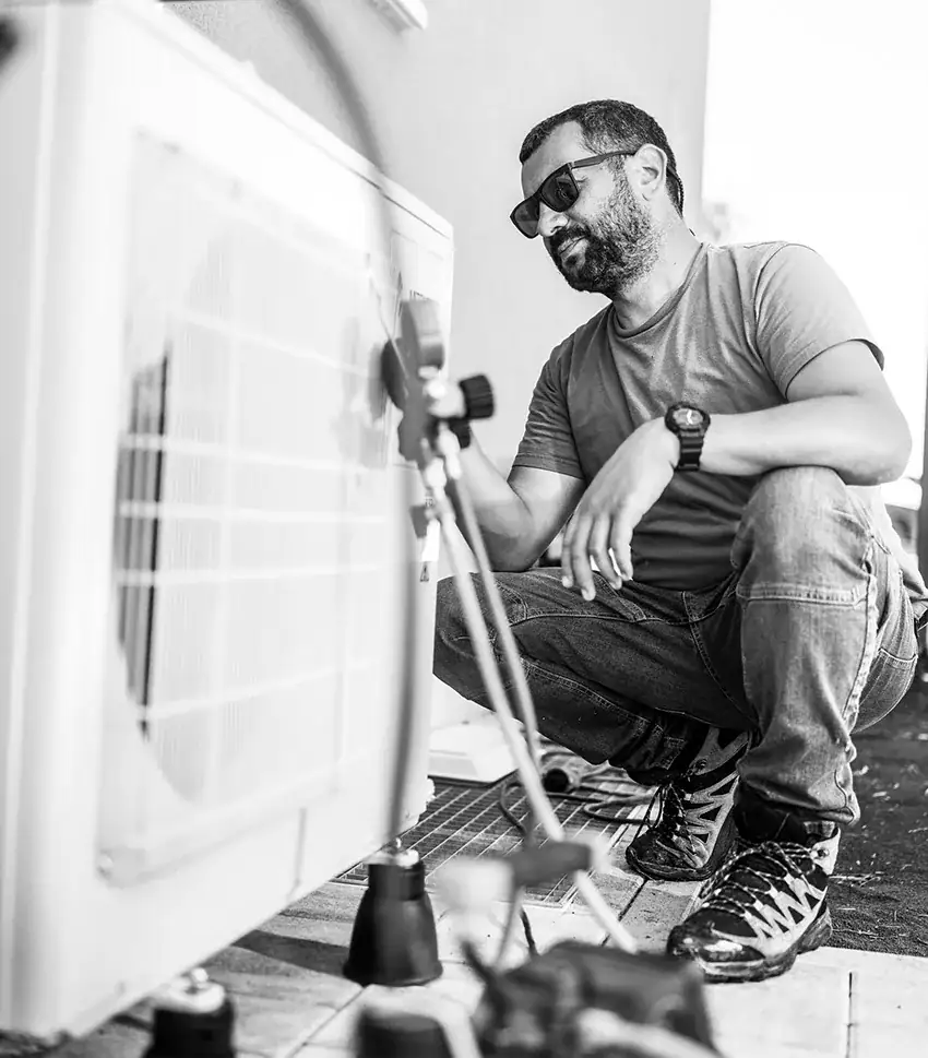 Man doing maintenance on a heat pump outside a home