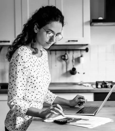 Woman calculating her finances at the kitchen counter.