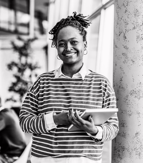Woman standing holding a notebook and smiling.